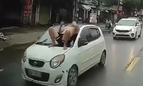 Người đàn ông nằm trên capo ô tô đang chạy giữa phố Hà Nội